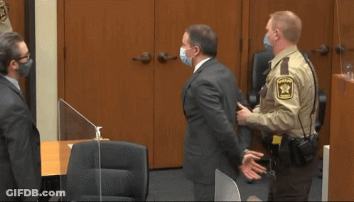 A Man In Handcuffs Is Escorted By Two Police Officers In Front Of A Door That Says C1874 GIF
