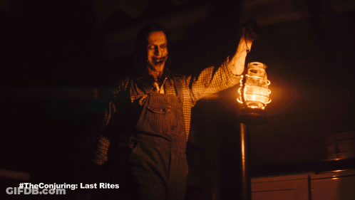 A Man In Overalls Is Holding A Lantern In A Dark Room GIF