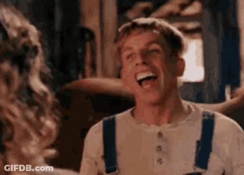 A Man In Overalls Is Laughing And Looking At A Woman . GIF