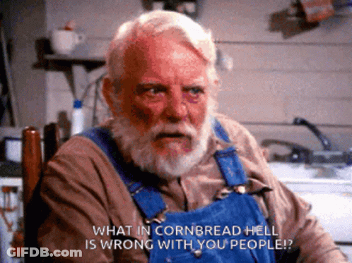 A Man In Overalls Is Sitting In A Chair And Says What In Cornbread Hell Is Wrong With You People GIF