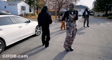 A Man In Overalls Is Walking Down A Street GIF