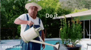 A Man In Overalls Is Watering Plants With A Watering Can . GIF