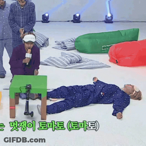 A Man In Pajamas Is Laying On The Floor With A Green Table In The Foreground GIF