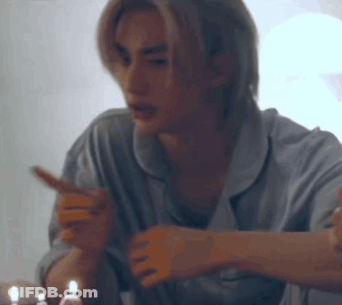 A Man In Pajamas Is Sitting At A Table With Candles In His Hand . GIF