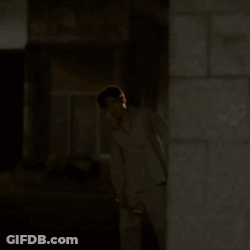 A Man In Pajamas Is Walking Down A Street At Night GIF
