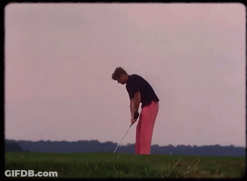 A Man In Pink Pants Is Swinging A Golf Club On A Green Field GIF
