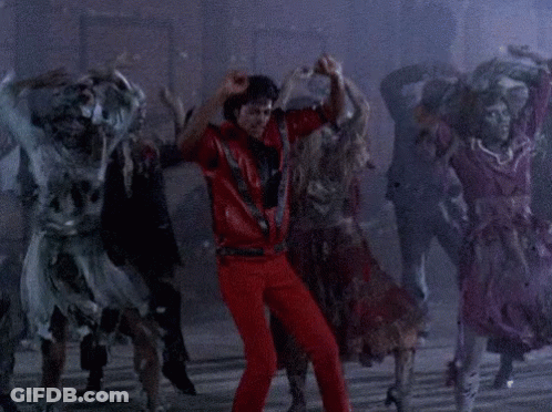 A Man In Red Pants Is Dancing With A Group Of Zombies Behind Him GIF