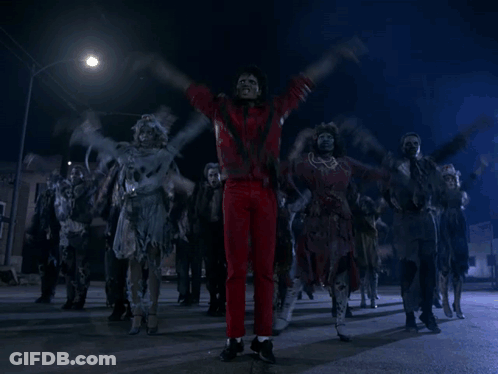 A Man In Red Pants Is Surrounded By Zombies On A Street GIF