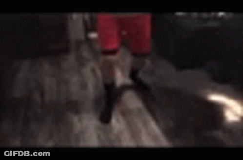 A Man In Red Shorts Is Standing In A Kitchen With His Arms Around His Chest . GIF