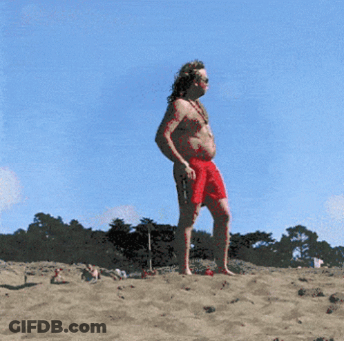 A Man In Red Shorts Is Standing On A Beach GIF