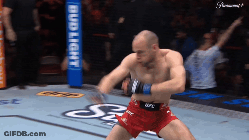 A Man In Red Shorts That Say UFC Is Dancing On A Boxing Ring GIF