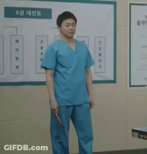 A Man In Scrubs Holds A Red Ping Pong Paddle GIF