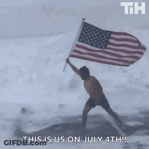 A Man In Shorts Is Holding An American Flag In The Snow GIF