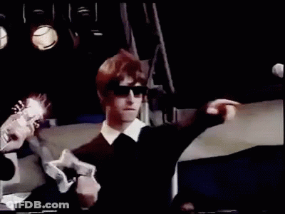 A Man In Sunglasses Is Playing A Guitar On Stage . GIF