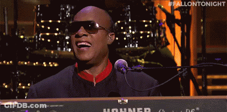 A Man In Sunglasses Is Singing Into A Microphone While Playing A Keyboard . GIF