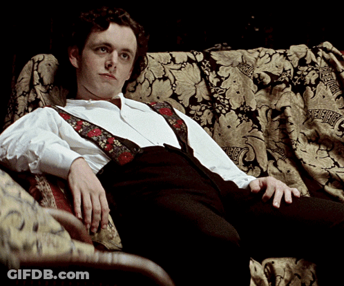 Man In Suspenders Sitting On Couch GIF