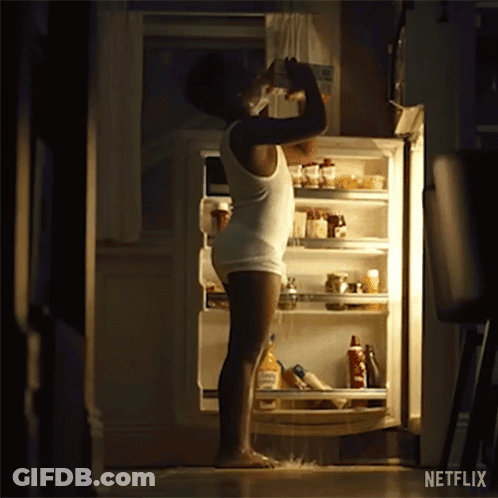 A Man In Underwear Is Standing In Front Of An Open Refrigerator At Night . GIF