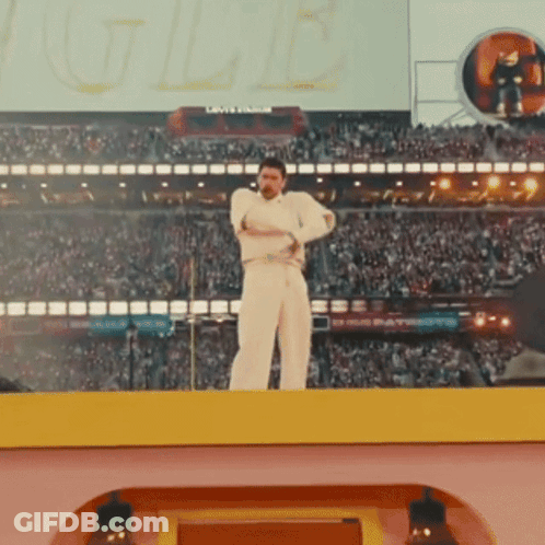 A Man In White Stands On A Stage In Front Of A Crowd And A Sign That Says ' Louisville ' On It GIF