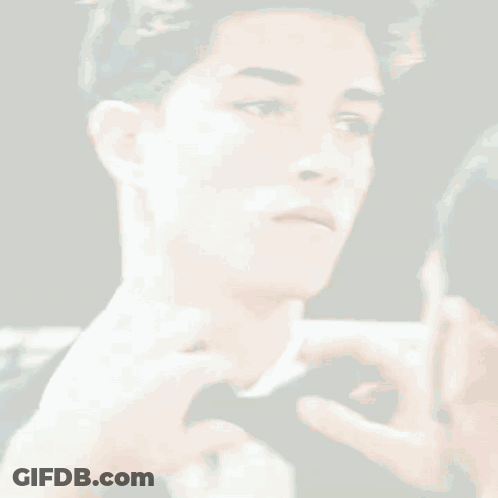 A Man Is Adjusting Another Man 'S Bow Tie In Front Of A Mirror GIF