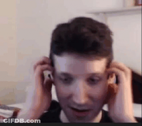 A Man Is Adjusting His Ear Buds While Sitting In Front Of A Computer Screen . GIF