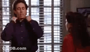 A Man Is Adjusting His Tie In Front Of A Woman In A Red Dress . GIF