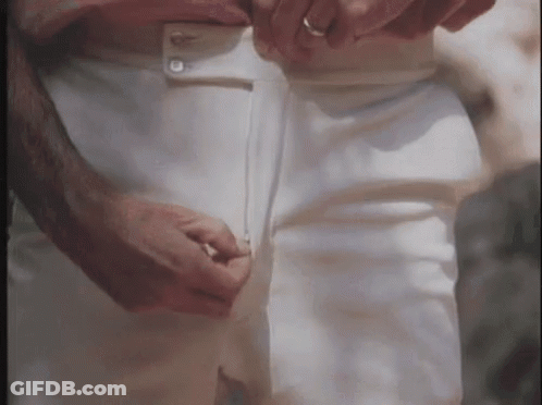 A Man Is Adjusting His White Pants While Wearing A Ring On His Finger . GIF