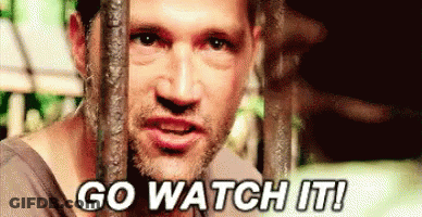 A Man Is Behind Bars With The Words `` Go Watch It '' Written On His Face . GIF