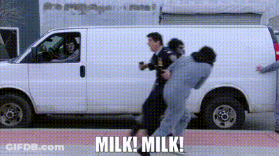 A Man Is Being Held By A Police Officer In Front Of A Van . GIF