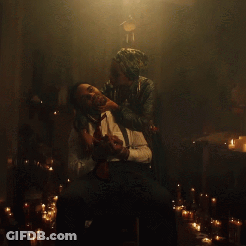 A Man Is Being Held By A Woman In A Dark Room With Candles GIF