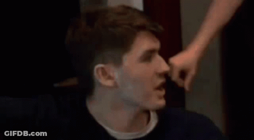 A Man Is Being Punched In The Face By Another Man While Sitting Down . GIF