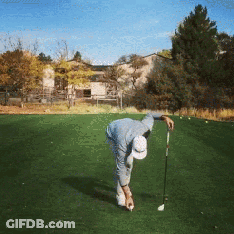 A Man Is Bending Over To Hit A Golf Ball On A Green GIF