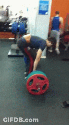 A Man Is Bending Over To Pick Up A Colorful Barbell GIF