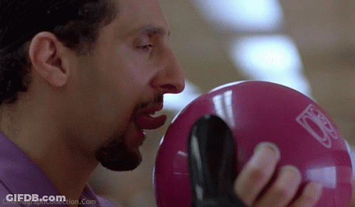 A Man Is Biting Into A Pink Bowling Ball With The Letter D On It GIF