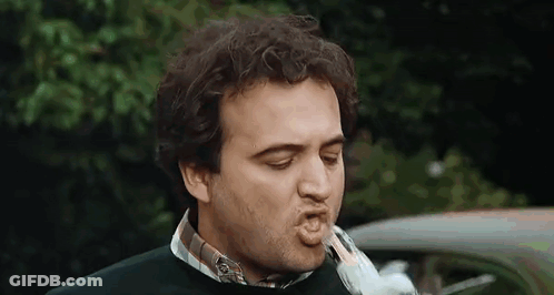 A Man Is Blowing A Kiss At A Bird While Standing In Front Of A Car . GIF