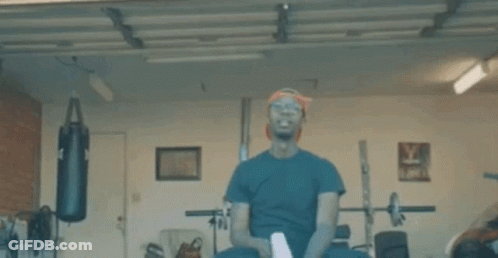 A Man Is Boxing In A Garage With A Red Light Coming Out Of His Eyes . GIF
