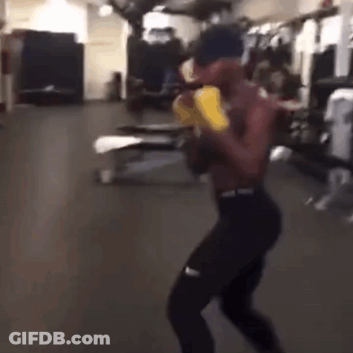 A Man Is Boxing In A Gym Without A Shirt On And Wearing Yellow Gloves . GIF
