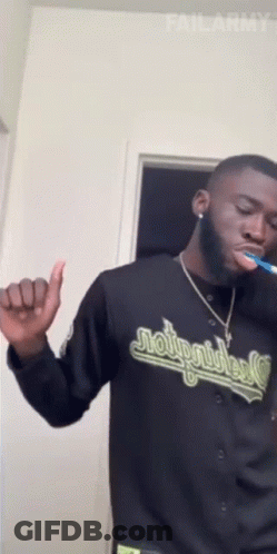 A Man Is Brushing His Teeth And Wearing A Jersey That Says Moto Riders GIF