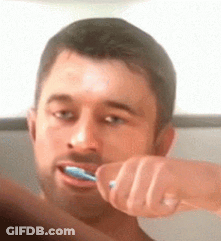 A Man Is Brushing His Teeth With A Blue Toothbrush In Front Of A Mirror . GIF