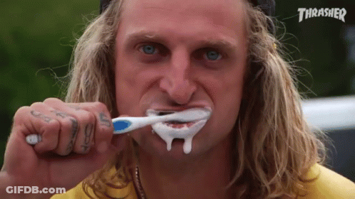 A Man Is Brushing His Teeth With A Thrasher Logo In The Background GIF