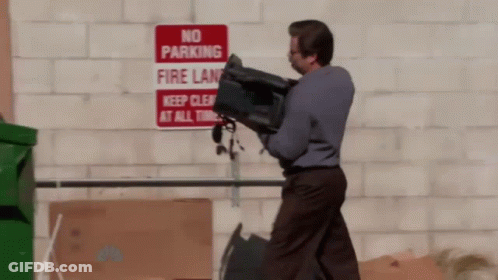 A Man Is Carrying A Bag In Front Of A No Parking Sign GIF