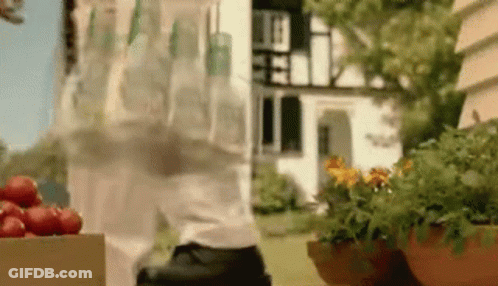 A Man Is Carrying A Bottle Of Water And A Box Of Strawberries In Front Of A House . GIF