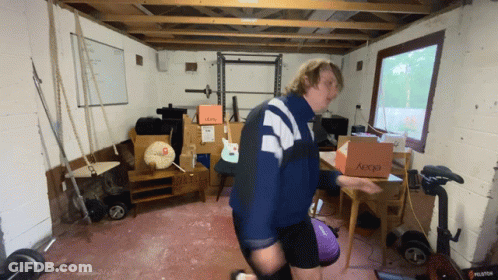 A Man Is Carrying A Box That Says Aeocd On It GIF