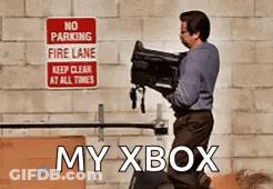 A Man Is Carrying A Camera In Front Of A No Parking Fire Lane Sign GIF