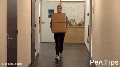 A Man Is Carrying A Cardboard Box Down A Hallway With Pen Tips Written On The Bottom Of The Image GIF