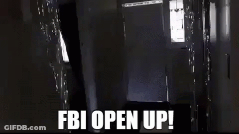 A Man Is Carrying A Large Box In A Hallway With The Words `` Fbi Open Up '' Written On It . GIF