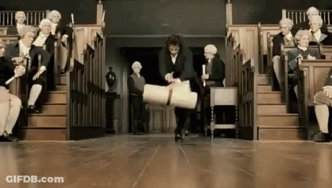 A Man Is Carrying A Large Piece Of Paper In Front Of A Group Of People Sitting In A Lecture Hall . GIF