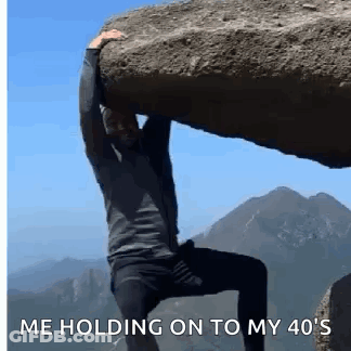 A Man Is Carrying A Large Rock On His Shoulders . GIF