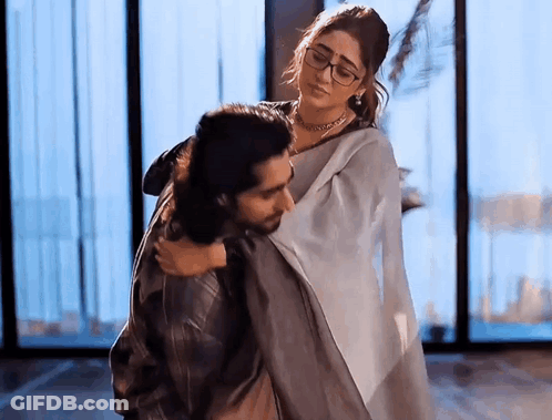 A Man Is Carrying A Woman In His Arms In A Room . GIF