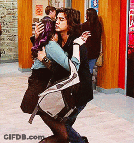 A Man Is Carrying A Woman In His Arms In Front Of A Sign That Says Co GIF