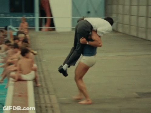 A Man Is Carrying A Woman Into A Pool GIF